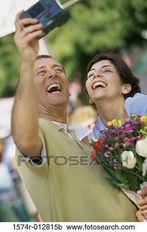 Close-up of a mature couple taking a photograph of themselves in a market View Large Photo Image Stock Image - Close-up of a mature couple taking a photograph of themselves in a market. Fotosearch