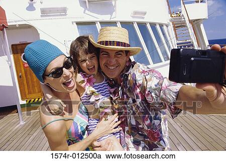 Stock Image - Close-up of a mid adult couple with their daughter taking a photograph of themselves. Fotosearch