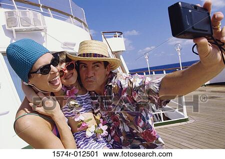 Stock Image - Close-up of a mid adult couple with their daughter taking a photograph of themselves. Fotosearch