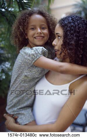 Stock Image - Close-up of a mother carrying her daughter. Fotosearch