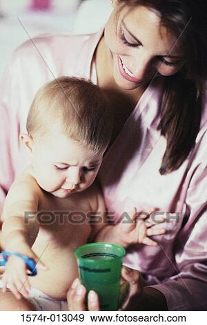 Stock Photo - Close-up of a mother holding a cup in front of her son. Fotosearch