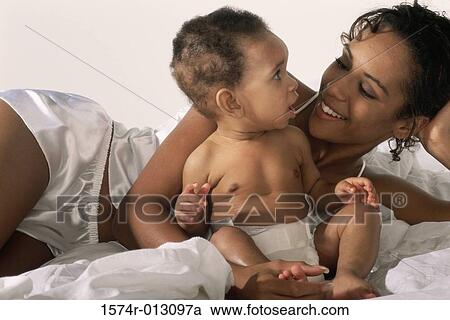 Stock Image - Close-up of a mother lying in bed playing with her son. Fotosearch