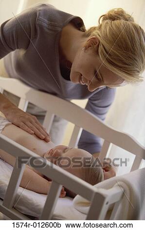 Stock Image - Close-up of a mother touching her son in a crib. Fotosearch