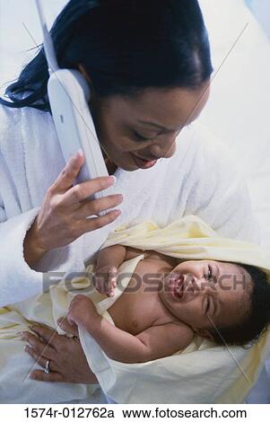 Close-up of a mother using a phone while holding her son View Large Photo Image Stock Image - Close-up of a mother using a phone while holding her son. Fotosearch