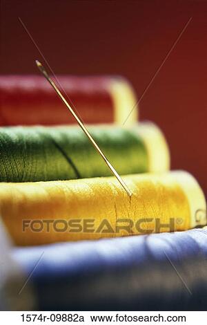 Stock Image - Close-up of a needle on spools of colored thread. Fotosearch