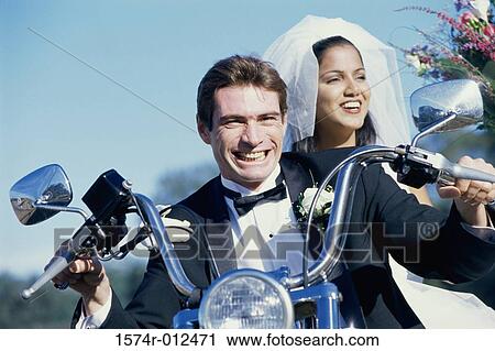 Stock Image - Close-up of a newlywed couple riding a motorcycle. Fotosearch