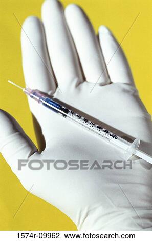 Stock Image - Close-up of a syringe on a person's hand. Fotosearch