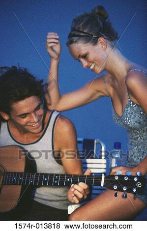 Close-up of a teenage boy playing a guitar with a teenage girl sitting beside him View Large Photo Image Stock Photo - Close-up of a teenage boy playing a guitar with a teenage girl sitting beside him. Fotosearch