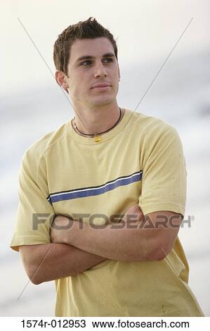 Stock Image - Close-up of a teenage boy standing with his arms crossed. Fotosearch
