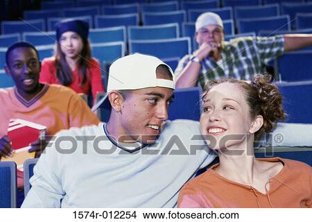 Close-up of a teenage couple sitting in a movie theater View Large Photo Image Picture - Close-up of a teenage couple sitting in a movie theater. Fotosearch