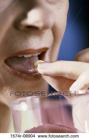 Close-up of a woman taking a pill View Large Photo Image Picture - Close-up of a woman taking a pill. Fotosearch