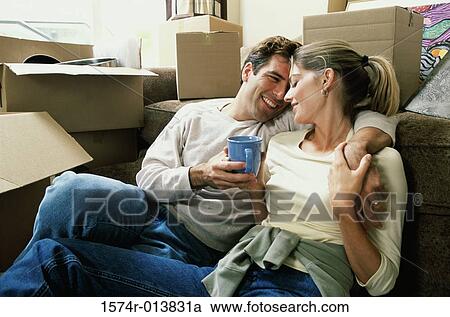 Stock Image - Close-up of a young couple holding a coffee cup sitting together. Fotosearch