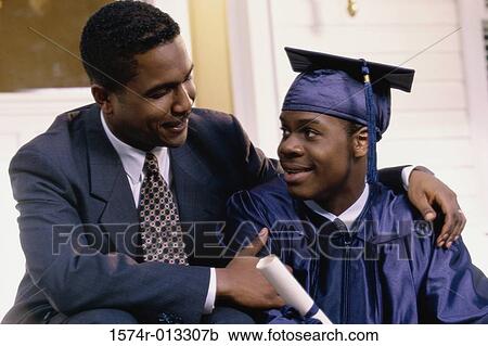 Stock Image - Close-up of a young male graduate sitting with his father. Fotosearch