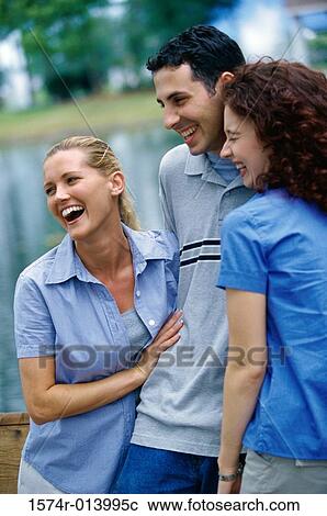 Stock Image - Close-up of a young man and two young women smiling. Fotosearch