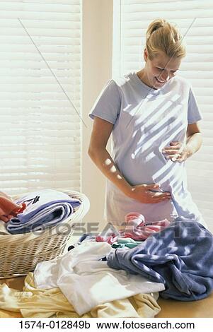 Stock Image - Close-up of a young pregnant woman touching her abdomen. Fotosearch