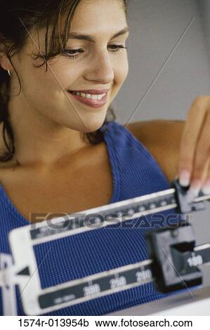 Close-up of a young woman adjusting a weight scale View Large Photo Image Stock Image - Close-up of a young woman adjusting a weight scale. Fotosearch