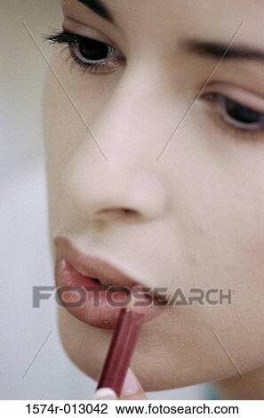 Stock Image - Close-up of a young woman applying lip liner. Fotosearch