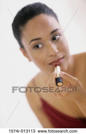 Close-up of a young woman applying lipstick View Large Photo Image Stock Image - Close-up of a young woman applying lipstick. Fotosearch