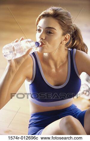 Stock Image - Close-up of a young woman drinking water from a water bottle. Fotosearch