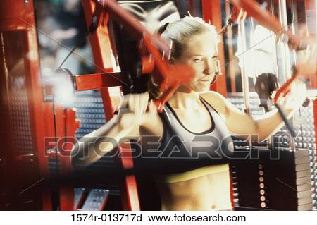 Close-up of a young woman exercising in a gym View Large Photo Image Stock Image - Close-up of a young woman exercising in a gym. Fotosearch