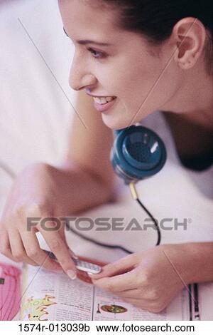 Stock Image - Close-up of a young woman filing her nails while talking on the telephone. Fotosearch