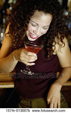 Stock Image - Close-up of a young woman holding a martini at a bar. Fotosearch