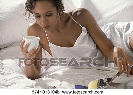 Close-up of a young woman lying on the bed and holding a cup of coffee View Large Photo Image Stock Image - Close-up of a young woman lying on the bed and holding a cup of coffee. Fotosearch