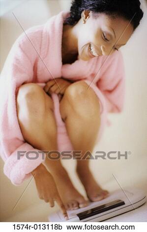 Close-up of a young woman squatting on a weight scale View Large Photo Image Stock Image - Close-up of a young woman squatting on a weight scale. Fotosearch