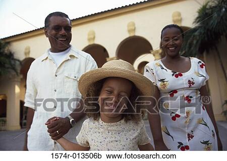 Stock Image - Close-up of grandparents walking with their granddaughter. Fotosearch
