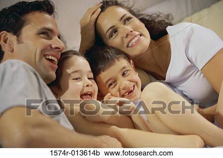 Stock Image - Close-up of parents and their two children playing in bed. Fotosearch