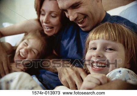 Stock Image - Close-up of parents and their two children playing in bed. Fotosearch