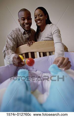 Close-up of parents looking at their son in a crib View Large Photo Image Stock Image - Close-up of parents looking at their son in a crib. Fotosearch