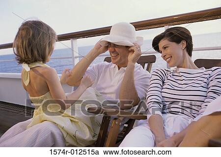 Stock Image - Close-up of parents sitting with their daughter on the deck of a cruise ship. Fotosearch
