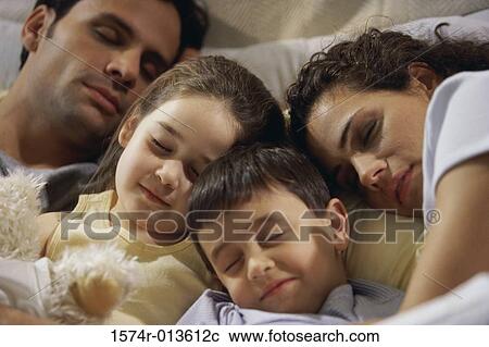 Close-up of parents with their two children sleeping on the bed View Large Photo Image Stock Image - Close-up of parents with their two children sleeping on the bed. Fotosearch
