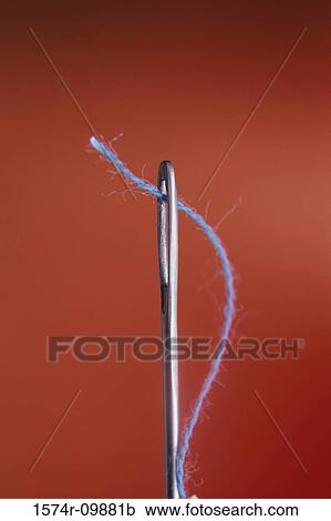 Stock Image - Close-up of thread through the eye of a needle. Fotosearch