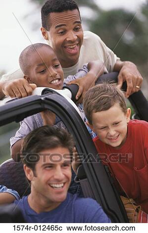 Stock Image - Close-up of two fathers with their sons in a jeep. Fotosearch