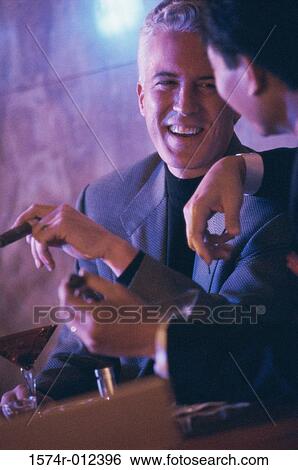 Stock Photograph - Close-up of two mid adult men talking in a bar. Fotosearch
