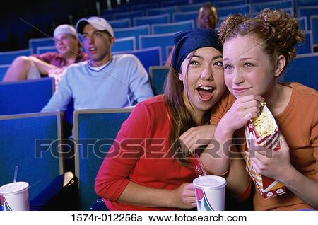 Close-up of two teenage girls sitting in a movie theater looking surprised View Large Photo Image Stock Image - Close-up of two teenage girls sitting in a movie theater looking surprised. Fotosearch
