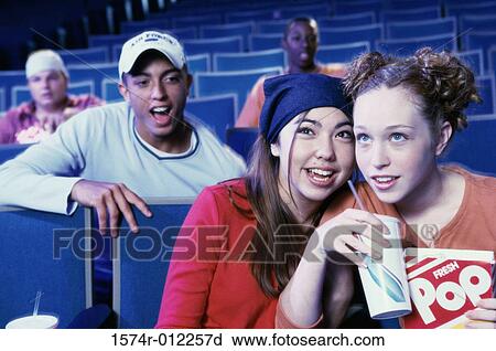 Stock Image - Close-up of two teenage girls sitting in a movie theater. Fotosearch