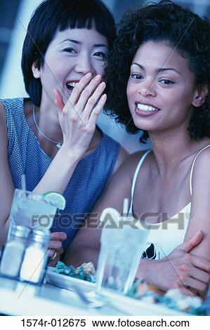 Stock Photography - Close-up of two young women whispering. Fotosearch