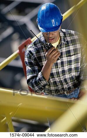 Picture - Construction worker talking on a walkie-talkie. Fotosearch
