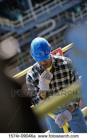 Construction worker talking on a walkie-talkie View Large Photo Image Stock Image - Construction worker talking on a walkie-talkie. Fotosearch
