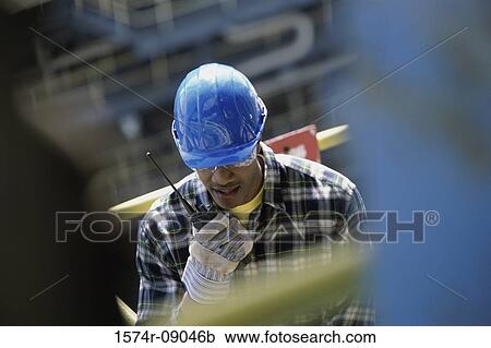 Construction worker talking on a walkie-talkie View Large Photo Image Stock Image - Construction worker talking on a walkie-talkie. Fotosearch