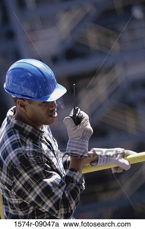 Construction worker talking on a walkie-talkie View Large Photo Image Stock Image - Construction worker talking on a walkie-talkie. Fotosearch