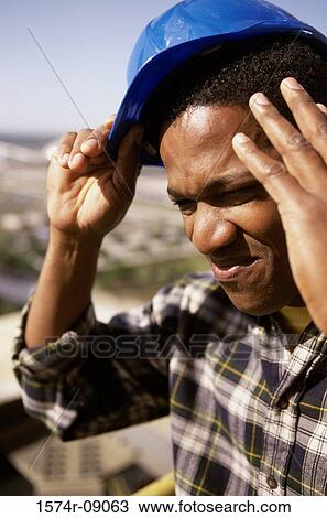 Construction worker touching his head and removing his hardhat View Large Photo Image Stock Image - Construction worker touching his head and removing his hardhat. Fotosearch