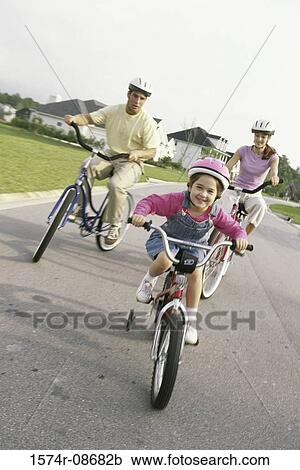 Stock Image - Daughter cycling with her parents. Fotosearch