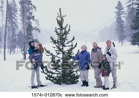 Family standing near a tree in snow View Large Photo Image Stock Image - Family standing near a tree in snow. Fotosearch
