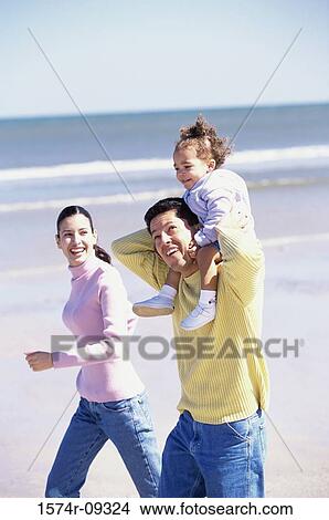 Father and mother on the beach carrying their daughter View Large Photo Image Picture - Father and mother on the beach carrying their daughter. Fotosearch