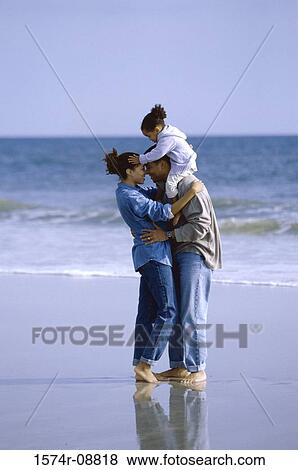 Father and mother on the beach carrying their daughter View Large Photo Image Stock Photo - Father and mother on the beach carrying their daughter. Fotosearch