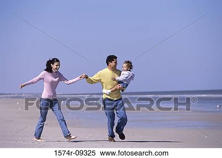 Stock Photography - Father and mother on the beach with their daughter. Fotosearch
